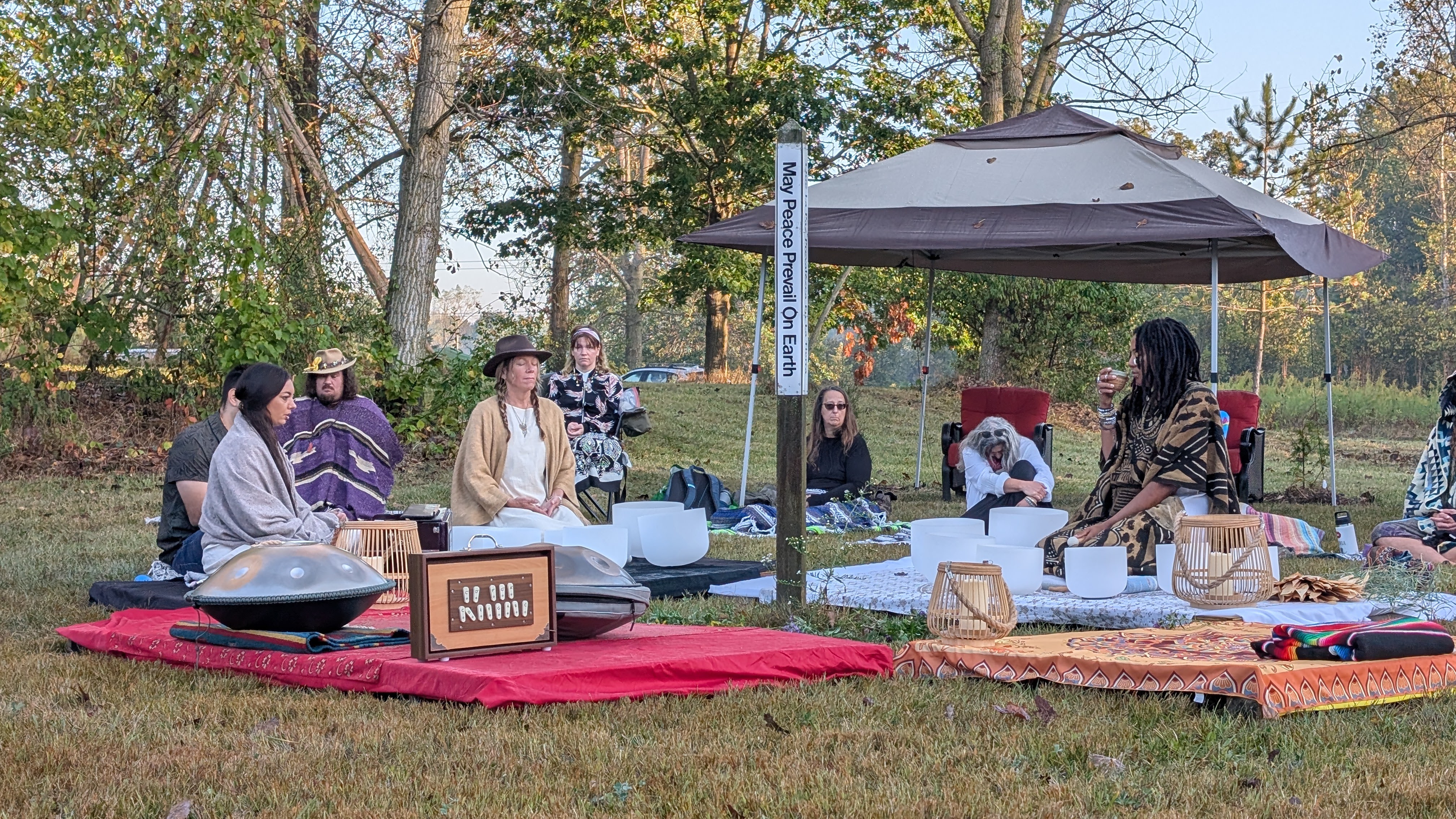 People seated with singing bowls and instruments in the Cedar Circle